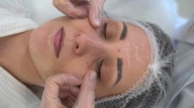 Yukarıdan gelen kozmetolog müşteriye masaj yapıyor, spa 'da ya da kuaförde işlem yapıyor. Cilt bakımı, kozmetoloji ve güzellik. 4k video