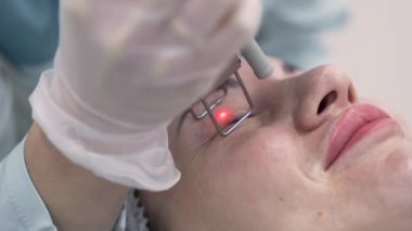 Extreme close up shot of Beautician cosmetologist doing procedure fractional microneedle mesotherapy rejuvenation with laser technology. Hardware cosmetology in clinic salon for client.
