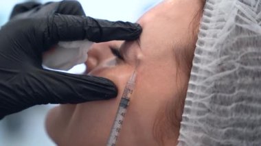 Güzellik uzmanı genç güzel bir kadının alnına botulinyum toksin enjekte ediyor. 4km 'lik atış çok yakın. Güzellik teknolojisi kavramı