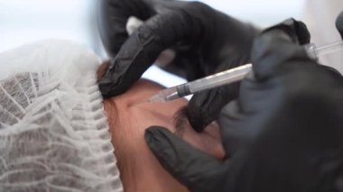 Güzellik uzmanı genç güzel bir kadının alnına botulinyum toksin enjekte ediyor. 4K dikey çekim için aşırı yakın çekim. Güzellik teknolojisi kavramı