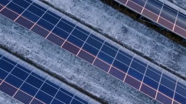 Kışın erken saatlerinde güneş batımında güneş çiftliğindeki büyük güneş panellerinin insansız hava aracı görüntüsü. Güneş pili santralleri. Renkli video 4k.