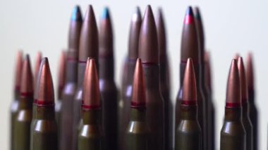 Farklı tipte mermiler beyaz arka planda, sığ alan derinliğinde, yakın planda dönüyorlar. Sosyal meseleler, savaş ve askeri kavram