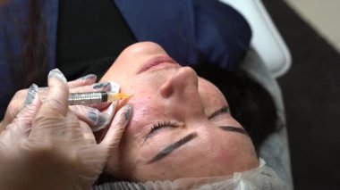 Kozmetik uzmanı kadın vücuduna birden fazla enjeksiyon yapıyor. Cilt elmacık kemiği, yakın çekim. Güzellik kliniğinde mezoterapi ve yüz gerdirme. Güzellik uzmanlarının elleri ve kızların yüzü.