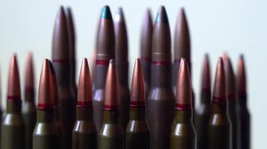 Farklı tipte mermiler beyaz arka planda, sığ alan derinliğinde, yakın planda dönüyorlar. Sosyal meseleler, savaş ve askeri kavram