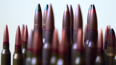 Farklı tipte mermiler beyaz arka planda, sığ alan derinliğinde, yakın planda dönüyorlar. Sosyal meseleler, savaş ve askeri kavram