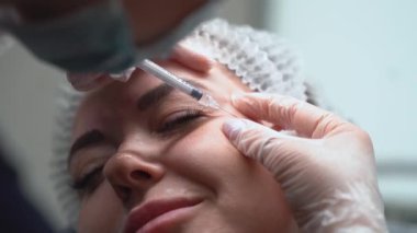 Güzellik uzmanı genç güzel bir kadının alnına botulinyum toksin enjekte ediyor. 4km 'lik atış çok yakın. Güzellik teknolojisi kavramı