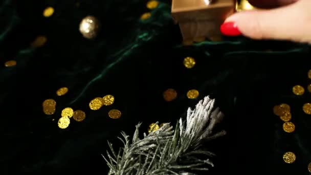 女性の手は クリスマスの装飾 フラットレイアウトと 輝きのベロアグリーンの背景に銀リボンと金のギフトボックスを置きます コピースペース 結婚クリスマス — ストック動画