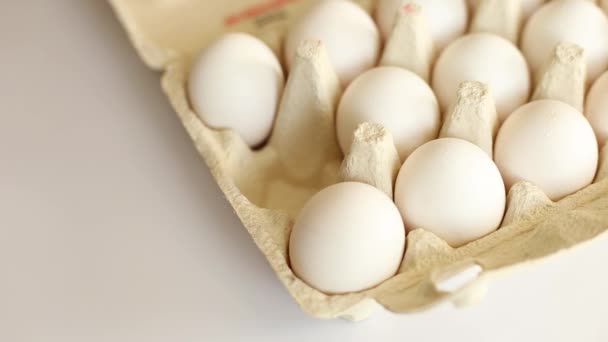 女性の手は白い背景に段ボール箱の卵から卵を取ります 有機卵パック製品 — ストック動画