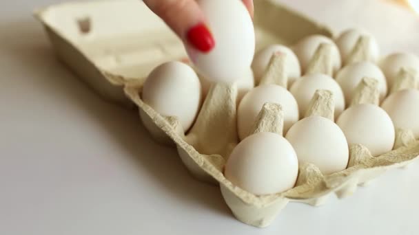 女性の手は白い背景に段ボール箱の卵から卵を入れ 有機卵パック製品 — ストック動画