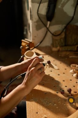 Elektrikli aletler kullanan bir kadın. Tahta çatal bıçak kaşığı, oyma makinesi, öğütme makinesi, el yapımı eşyalar, atölyede bir kadın..