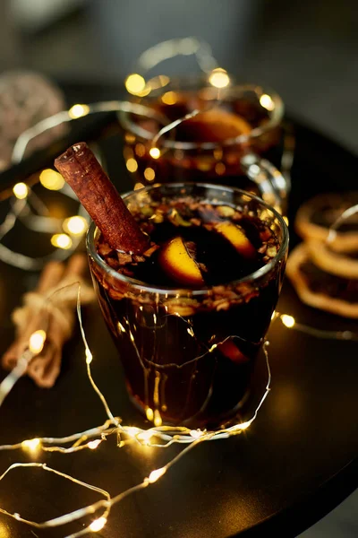 Χριστουγεννιάτικο Κόκκινο Κρασί Μπαχαρικά Και Πορτοκάλια Μαύρο Τραπέζι Ελαφριά Γιρλάντα — Φωτογραφία Αρχείου