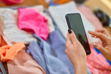Tanınmayan kadın valizini hazırlıyor, akıllı telefondan eşyaları kontrol ediyor, yaz tatili için hazırlanıyor tatiller için bavulları hazırlıyor..