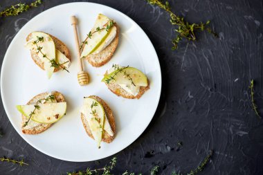 Siyah arka planda beyaz tabakta armut ve mavi peynirli sandviç veya bruschetta, boşluğu kopyala.