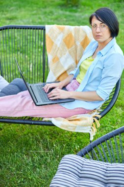 Bilgisayarda uzaktan çalışan bir kadın el bilgisayarı, laptopla çalışan serbest çalışan bir kadın, sosyal medyayı kontrol eden, internetten alışveriş yapan, bahçedeki arka bahçede eve sipariş veren bir kadın.