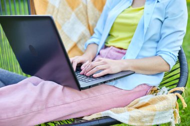 Bilgisayarda uzaktan çalışan bir kadın el bilgisayarı, laptopla çalışan serbest çalışan bir kadın, sosyal medyayı kontrol eden, internetten alışveriş yapan, bahçedeki arka bahçede eve sipariş veren bir kadın.