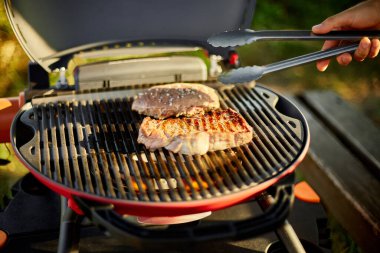 Adam gaz ızgarasında et kızarttı arka bahçede ızgara ızgara et, ızgara et, yaz aile pikniği, doğada yemek..