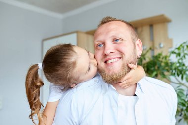 Beyazlar içindeki baba ve kızı evde vakit geçiriyorlar, yakışıklı adam küçük tatlı kızıyla oynuyor, birlikte rahatça vakit geçiriyorlar, Babalar Günün kutlu olsun..