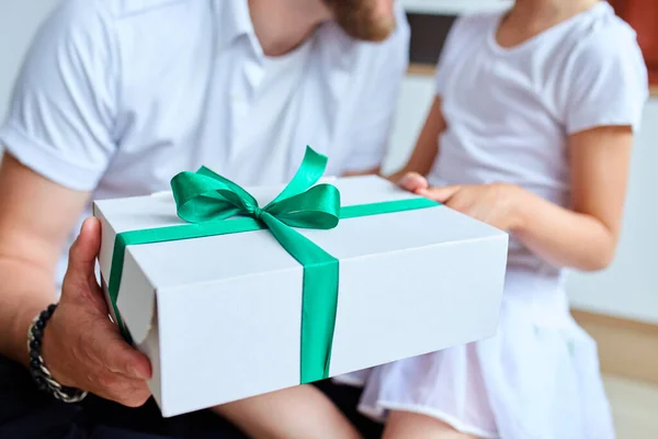 Unrecognizable daughter congratulating dad and giving present on birthday at home, little girl is giving her handsome father a gift box on Father\'s day. I love you, dad. Happy Father\'s Day.
