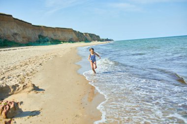 Happy, joyful little girl run on the beach , sea family vacation, Resort fun by the sea