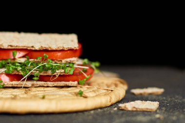 Sağlıklı vejetaryen sandviçi, kıtır çavdar ekmeği domates ve koyu arka planda mikro yeşillikler, diyet gıdalar..