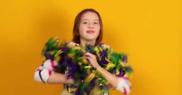 カラフルなブラジルのカーニバルマスクを身に着けている楽しい10代の女の子 ポーズ 黄色のスタジオの背景で楽しみを持っています お祝いの準備ができて 誕生日パーティー 休日のコンセプト — ストック動画