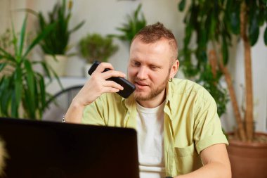Evde dizüstü bilgisayarla çalışan serbest çalışan bir adam, akıllı telefonda sanal komut asistanı, sesli çeviri uygulaması reklamı, yeni teknoloji kavramı kullanan bir adam.