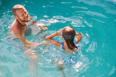Baba ve kızı evlerinde yüzme havuzunda eğleniyorlar arka bahçede, yaz zamanı, açık havada.
