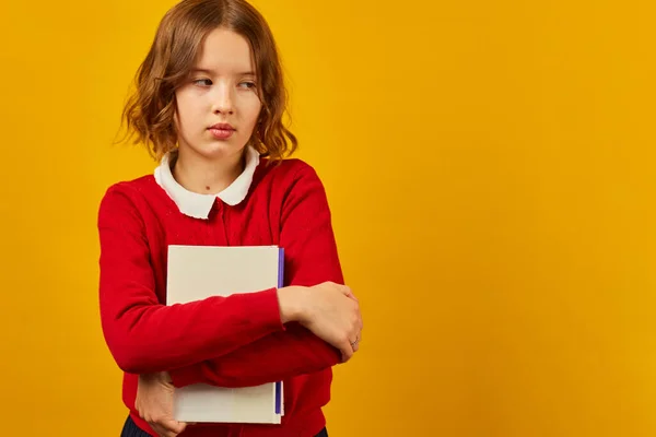 stock image Sad teenage schoolgirl holding hugs the book in hand on yellow studio background, educatin concept, , Back to School, copy space.