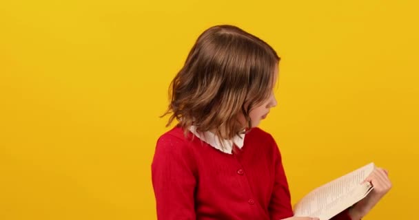 幸せな女子高生読書A本の黄色のスタジオの背景 教育の概念 バックへ学校 コピースペース 十代の女の子の学校の制服 — ストック動画