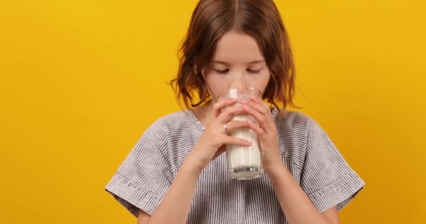 漂亮的少女 带着新鲜的牛奶的孩子被隔离在工作室的黄色背景 强壮的骨骼 牛奶的成长 健康的生活方式概念 复制空间 — 图库视频影像
