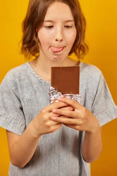 Красивая Девушка Подросток Шоколадкой Изолированы Студийном Желтом Фоне Наслаждаясь Десертом — стоковое фото