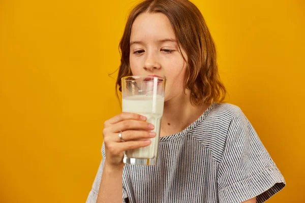 漂亮的少女 带着新鲜的牛奶的孩子被隔离在工作室的黄色背景 强壮的骨骼 牛奶的成长 健康的生活方式概念 复制空间 — 图库照片