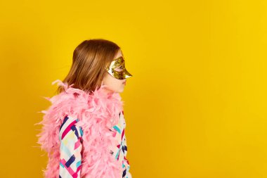 A joyful teenager girl wearing a colorful Brazil carnival mask, posing on yellow studio background, ready for celebration, birthday party, holidays concept