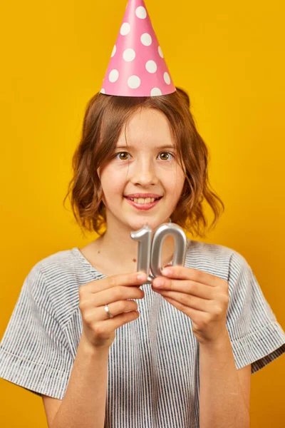 Fröhliches Positives Zehnjähriges Geburtstagskind Partyhut Mit Kerzen Glücklich Auf Gelbem lizenzfreie Stockbilder