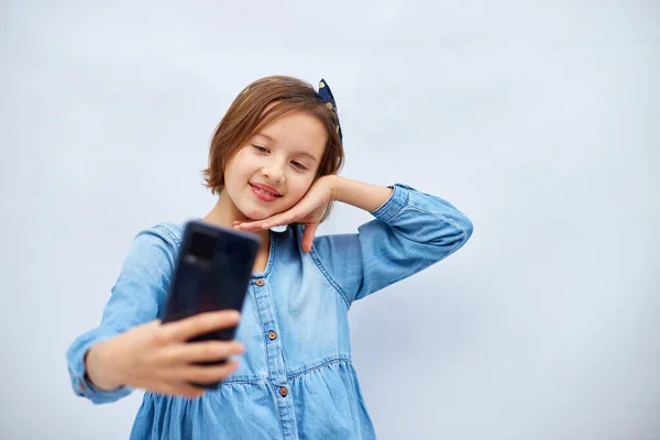 Smiling Little Girl Casual Denim Dress Hold Smartphone Selfie Shot — Zdjęcie stockowe
