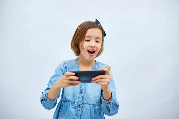 Fun Excited Kid Girl Casual Denim Dress Use Smartphone Enjoys — Zdjęcie stockowe