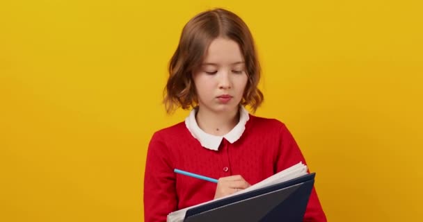 Przemyślane Nastolatka Szkoła Trzymając Długopis Pisać Notatniku Żółtym Tle Studio — Wideo stockowe