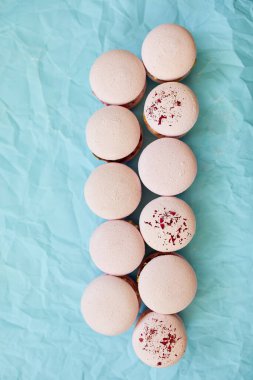 Mavi arka planda çeşitli tatlı Fransız pembe badem kurabiyeleri, tatlı bir hoşgörü..