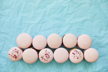 Mavi arka planda çeşitli tatlı Fransız pembe badem kurabiyeleri, tatlı bir hoşgörü..
