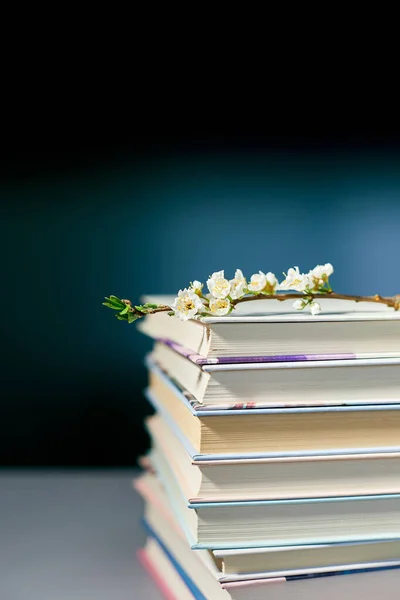 Stack of books with branch flowers, World book day, knowledge and creativity concept, spring, summer mood, copy space.