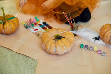 Turuncu balkabağını süsleyen genç bir kızın el resmi, Cadılar Bayramı için evde boyayla Jack-O-Lantern 'in yüzünü çiziyor. Tatil dekorasyonu kavramı