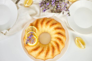 Beyaz masada, lavanta çiçekli limonlu kek manzarası.
