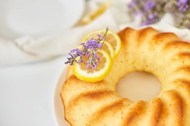 Beyaz masada lavanta çiçekli yuvarlak limonlu kek.