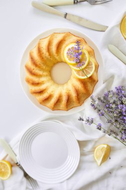 Beyaz masada, lavanta çiçekli limonlu kek manzarası.