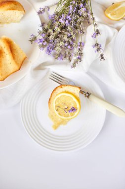 Beyaz masada, lavanta çiçekli bir dilim limonlu kek.