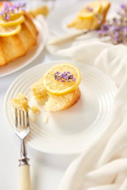 Beyaz masada, lavanta çiçekli bir dilim limonlu kek.