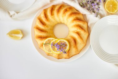 Beyaz masada, lavanta çiçekli limonlu kek manzarası.