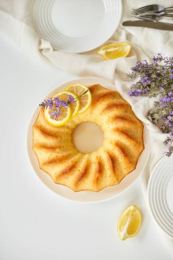 Beyaz masada, lavanta çiçekli limonlu kek manzarası.