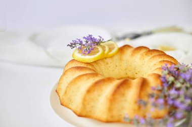 Beyaz masada lavanta çiçekli yuvarlak limonlu kek.