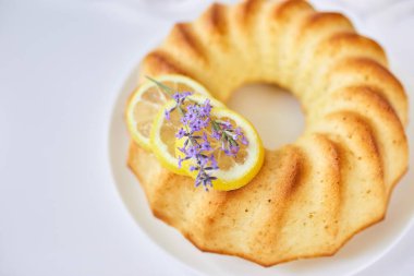 Beyaz masada lavanta çiçekli yuvarlak limonlu kek.